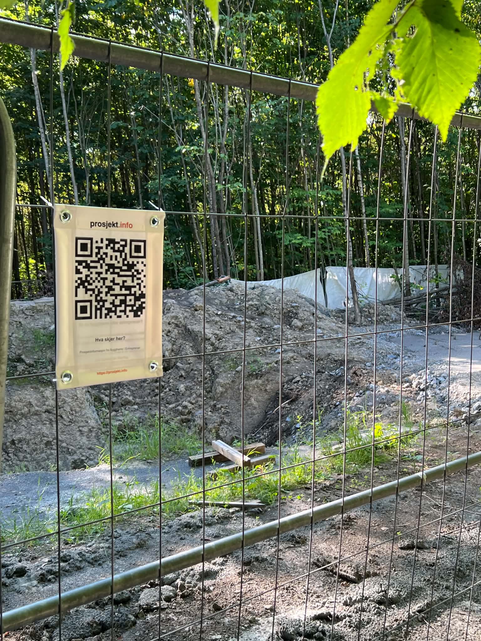 Skiltet med QR-kode montert på byggegjerde i skogen